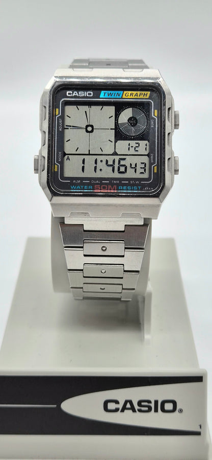 A Casio dual display analog watch with a silver-toned metal case and link bracelet, mounted on a white display stand with a Casio-branded base.