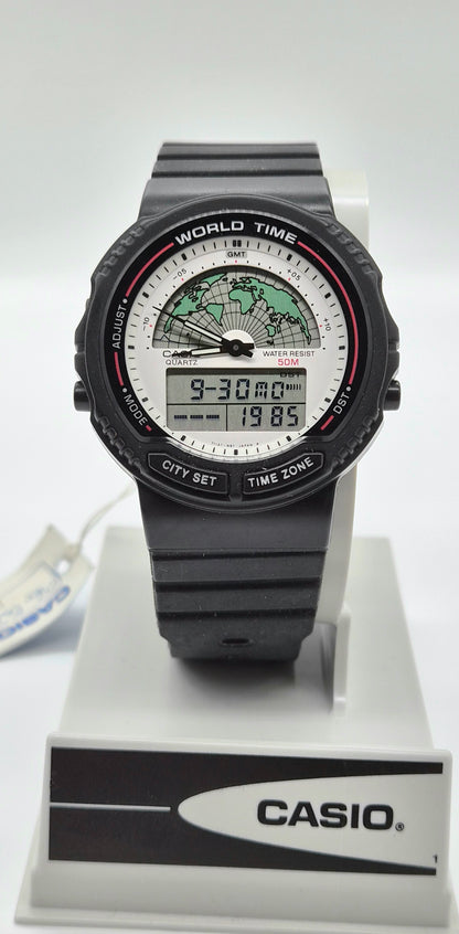 A Casio World Time digital watch with a black strap and case, featuring a white dial with a green world map graphic and digital time display, shown on a white display stand with a Casio logo.