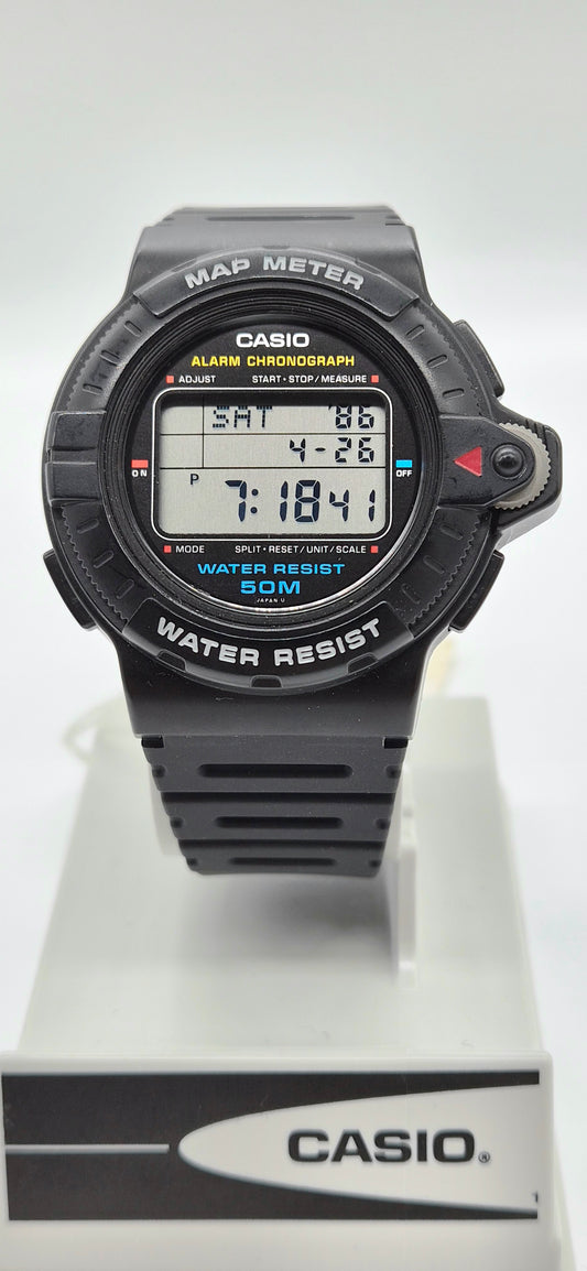 A Casio digital map and compass watch with a black strap and case, displayed on a white stand with a branded base against a white background.