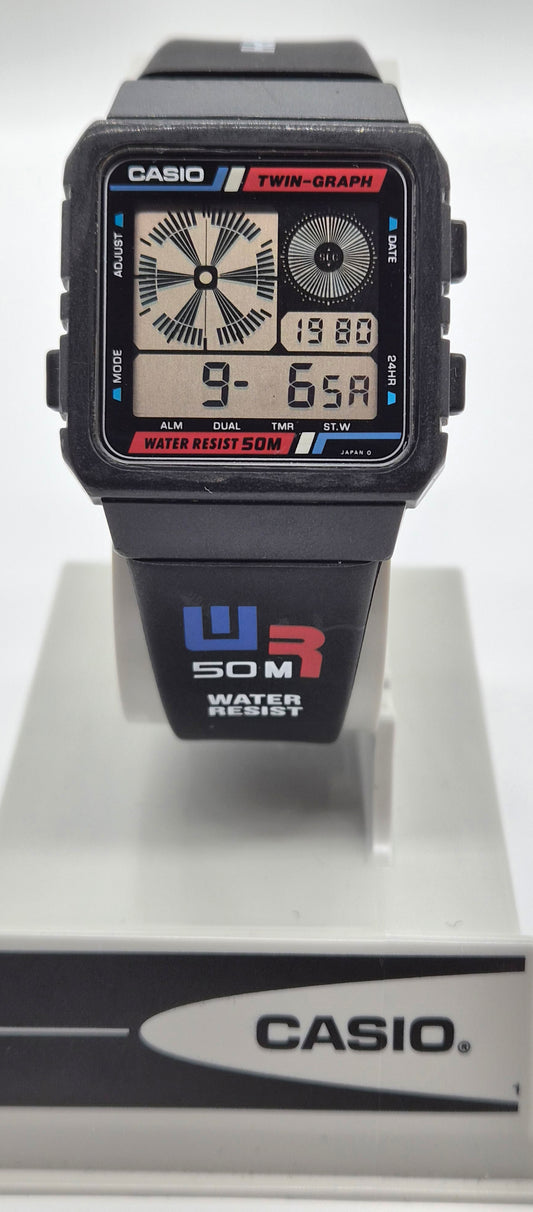 A Casio dual display watch with a black resin case and strap, featuring analog and digital screens, shown on a white display stand with a Casio-branded base.